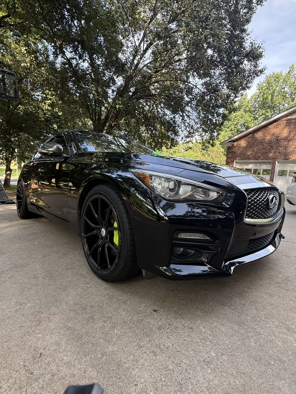 Black Infiniti Q50 with mirror-gloss paint and green calipers after a detail
