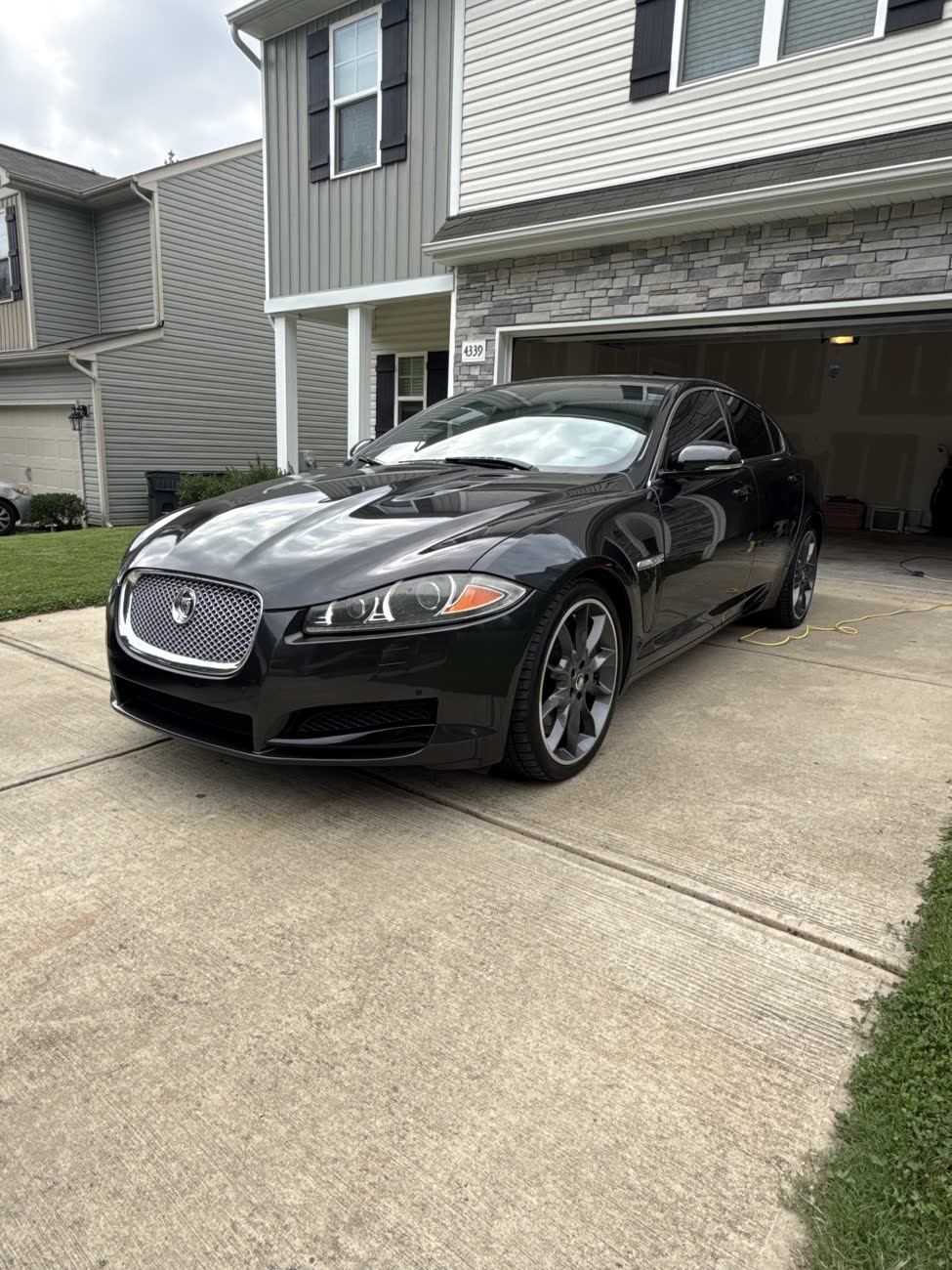 Dark grey Jaguar XF with a glossy finish in a customer driveway