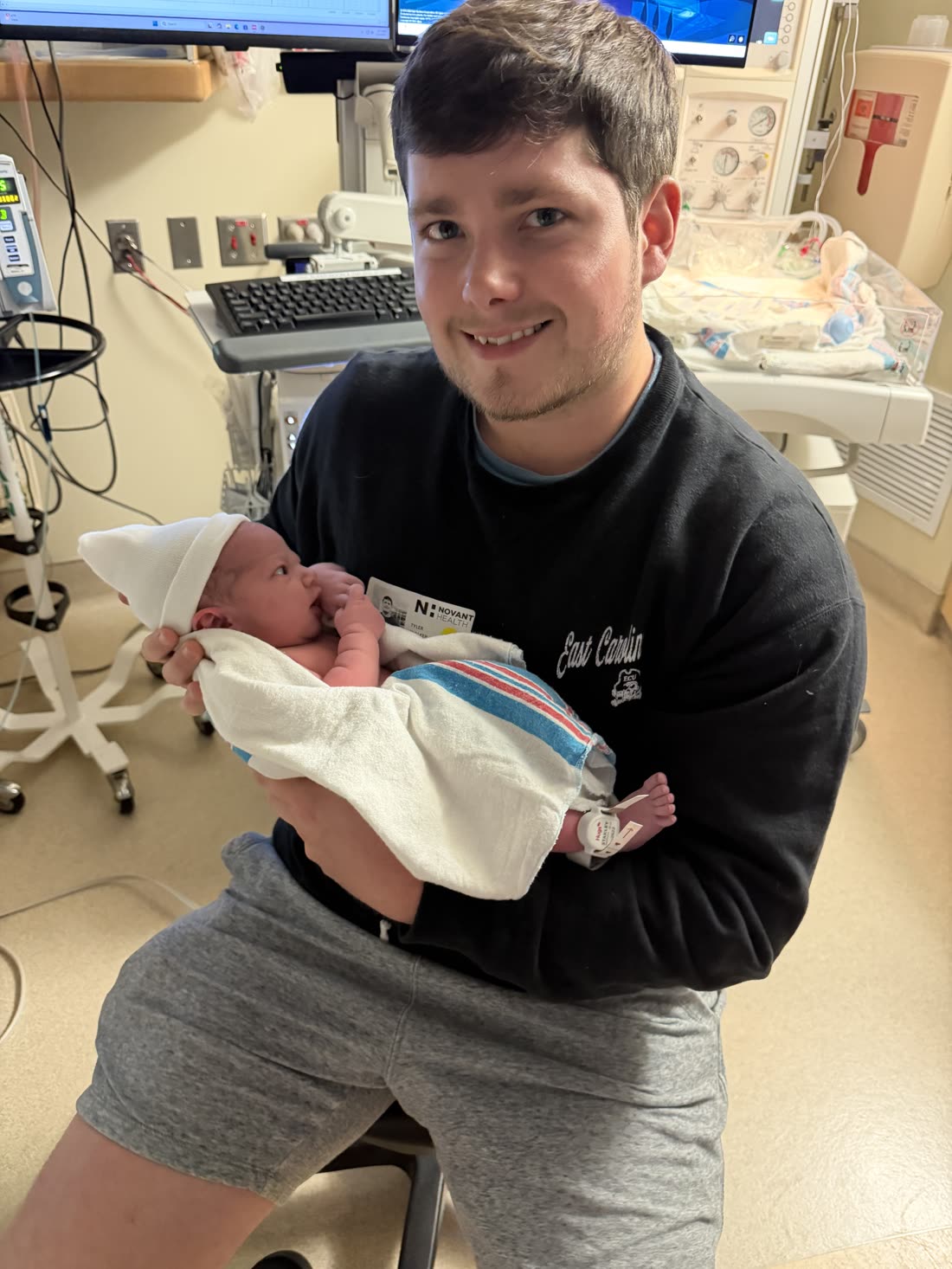 Tyler, the owner of Driveway Gloss, holding his newborn baby